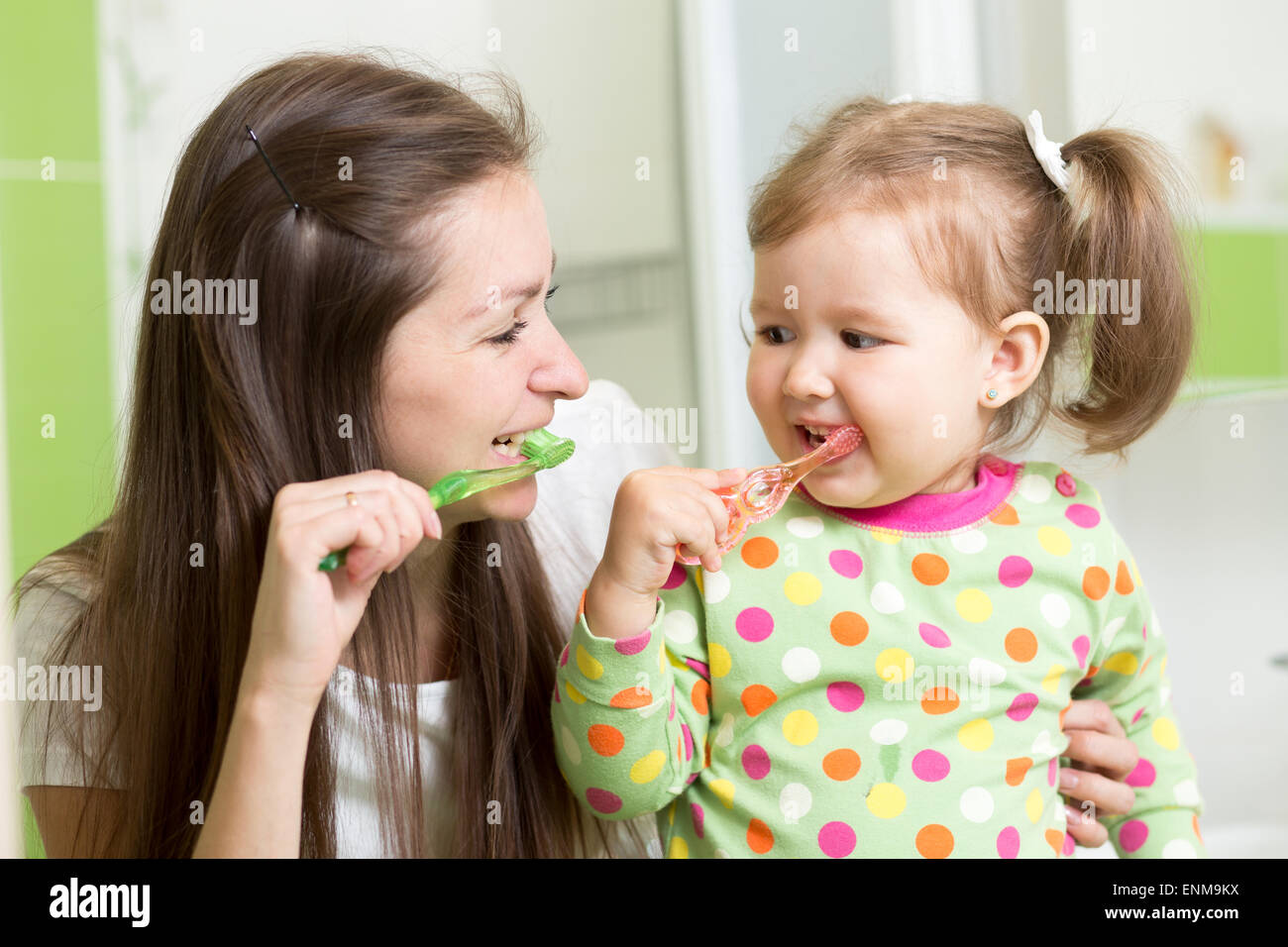 L'enseignement de mère fille enfant le brossage des dents dans la salle de bains Banque D'Images