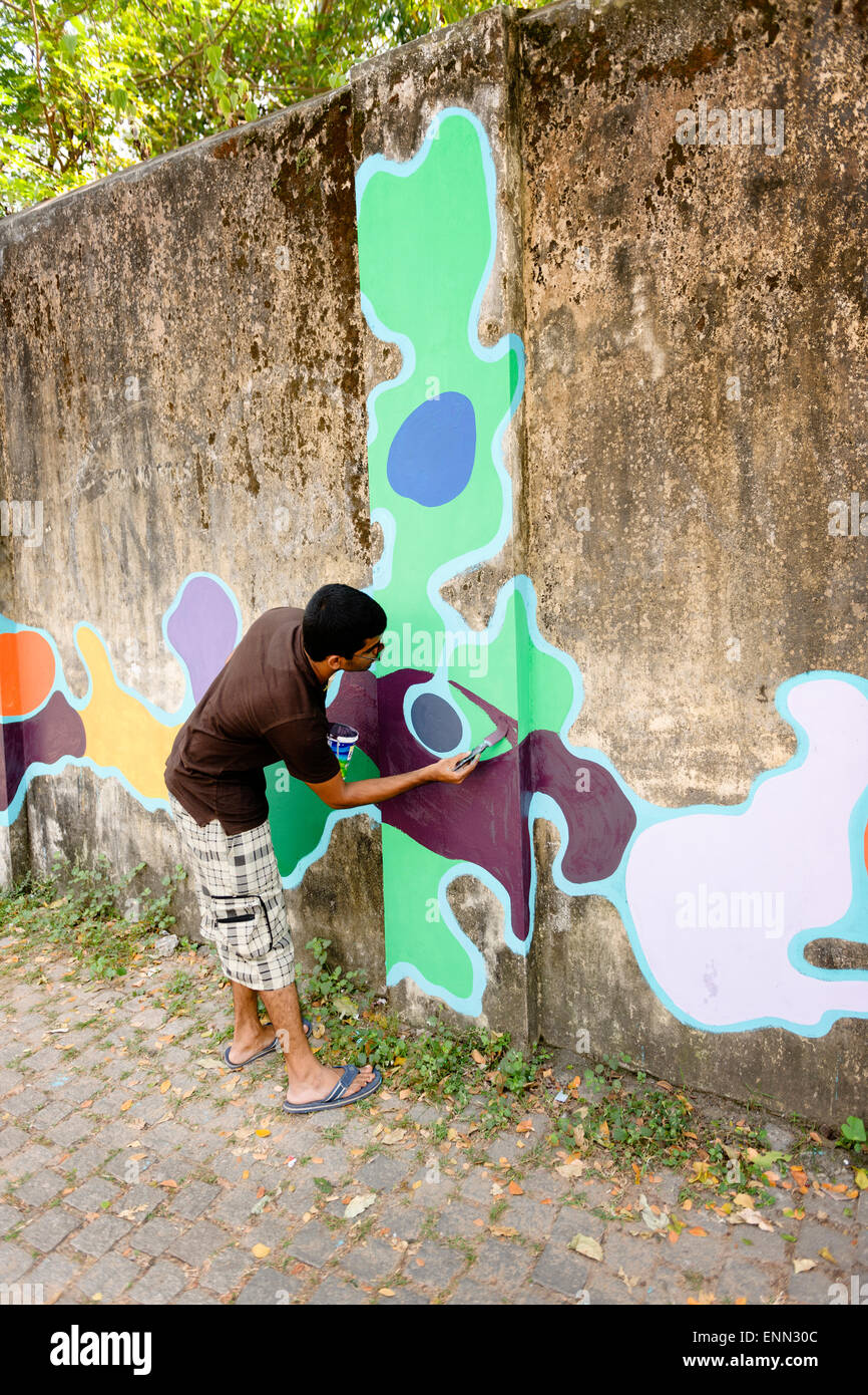 Rue locale-artiste décorant un mur de fort Kochi. Banque D'Images