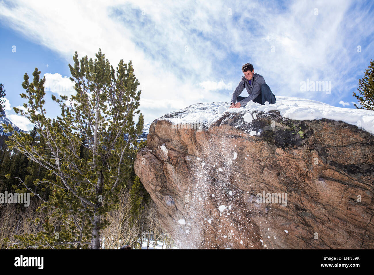 Grimpeur mâle nettoie la neige au sommet d'un rocher dans le Parc National des Montagnes Rocheuses, au Colorado Banque D'Images