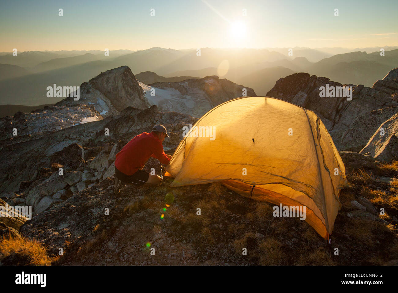 Un randonneur met en place une tente sur le sommet du pic de saxifrage, Pemberton, Canada. Banque D'Images