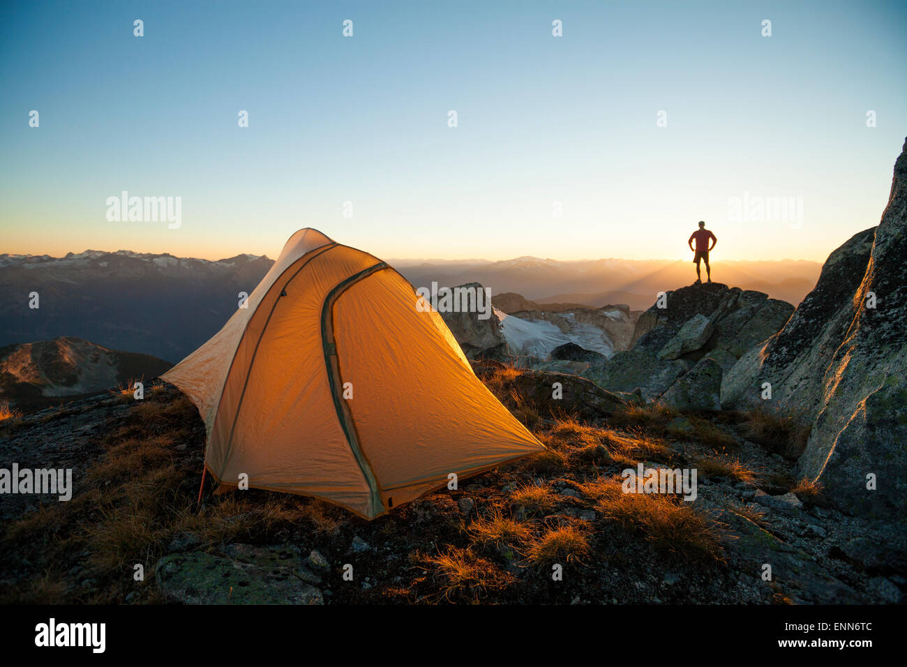 La silhouette d'un randonneur se dresse sur un promontoire rocheux tout en camping à pic, Saxifrage Pemberton, BC, Canada. Banque D'Images