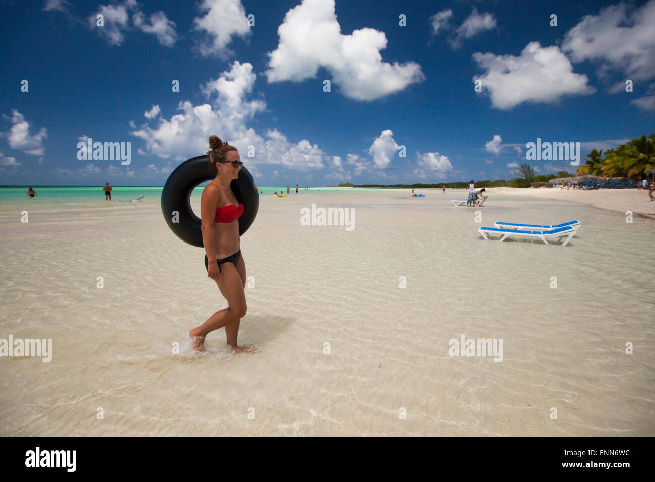 Une jeune femme porte son tube gonflable retour à la plage en vacances à Cayo Coco, Cuba. Banque D'Images