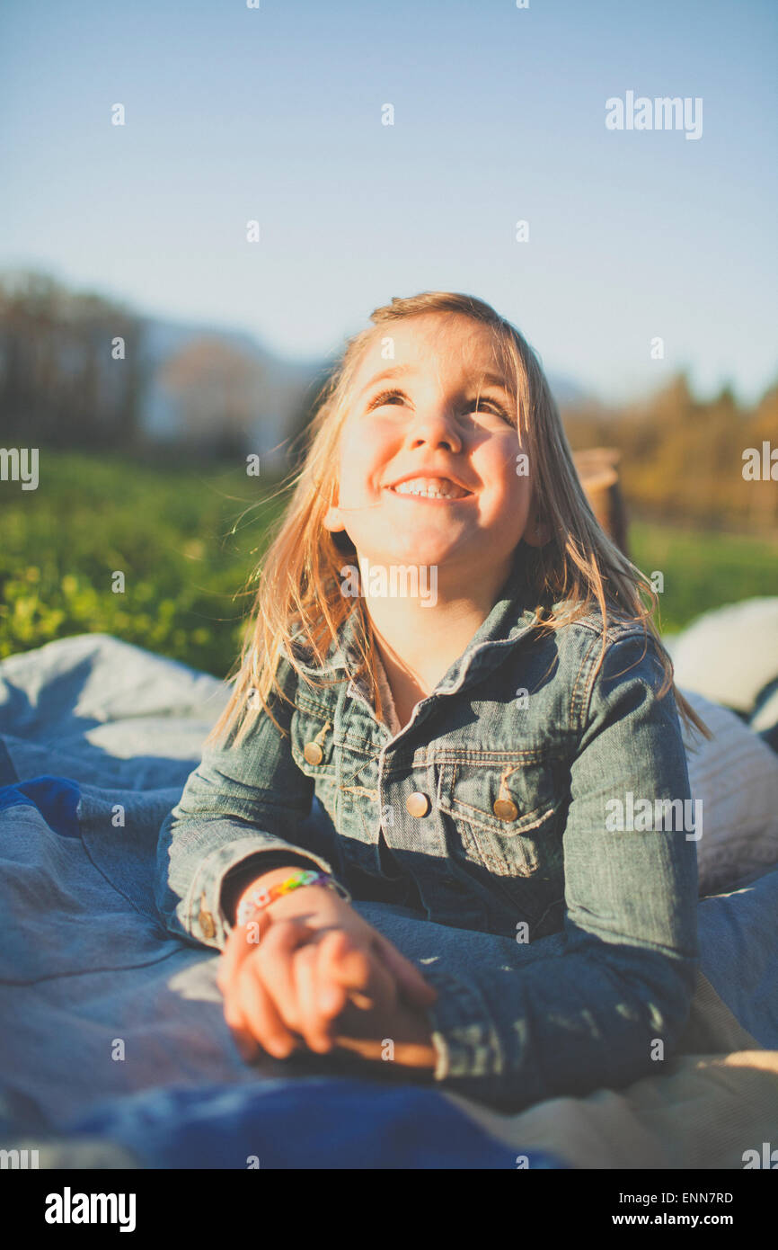 Une jeune fille lève les yeux vers le ciel tout en portant sur une couverture à l'extérieur de jean. Banque D'Images