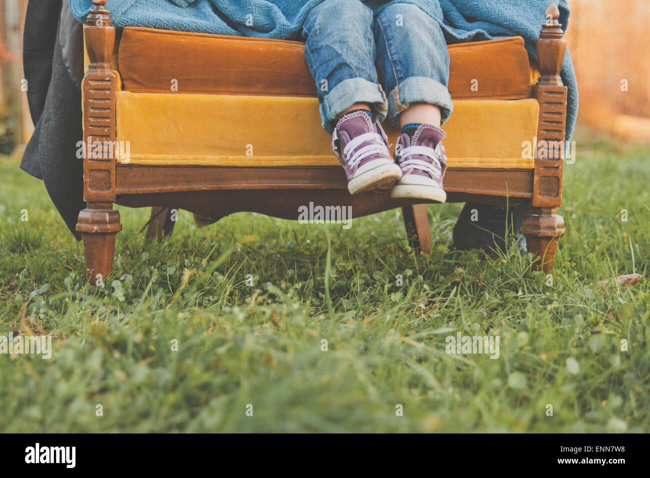 Un des jeunes garçons pieds pendre à l'extrémité d'une vieille chaise dans les champs. Banque D'Images