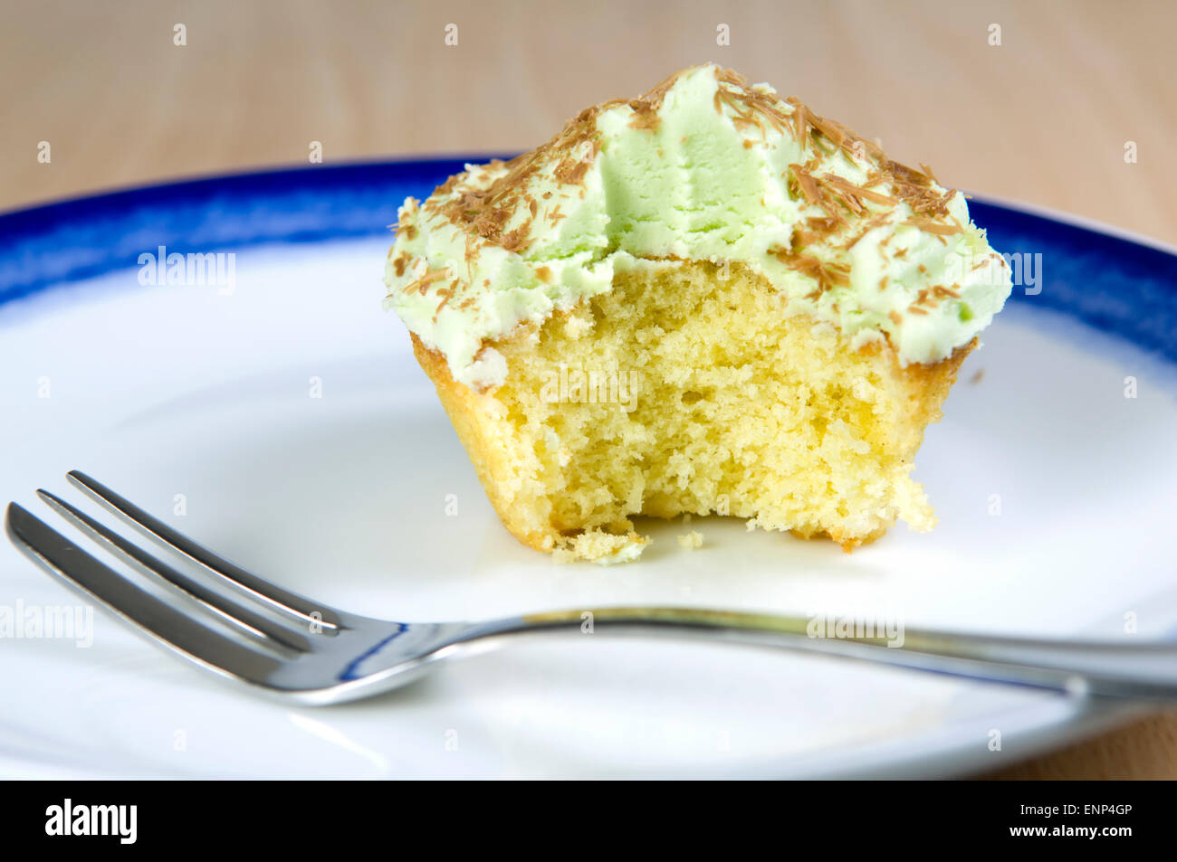 Cupcake pistache avec des copeaux de chocolat, glaçage vert et une collation prise hors de, sur une plaque bleu et blanc Banque D'Images