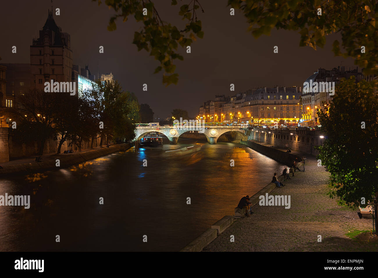 Les gens à trouver un peu de silence sur la Seine au-dessous de l'ensemble de l'activité dans le centre de Paris. Pont Saint-Michel est en arrière-plan. Banque D'Images