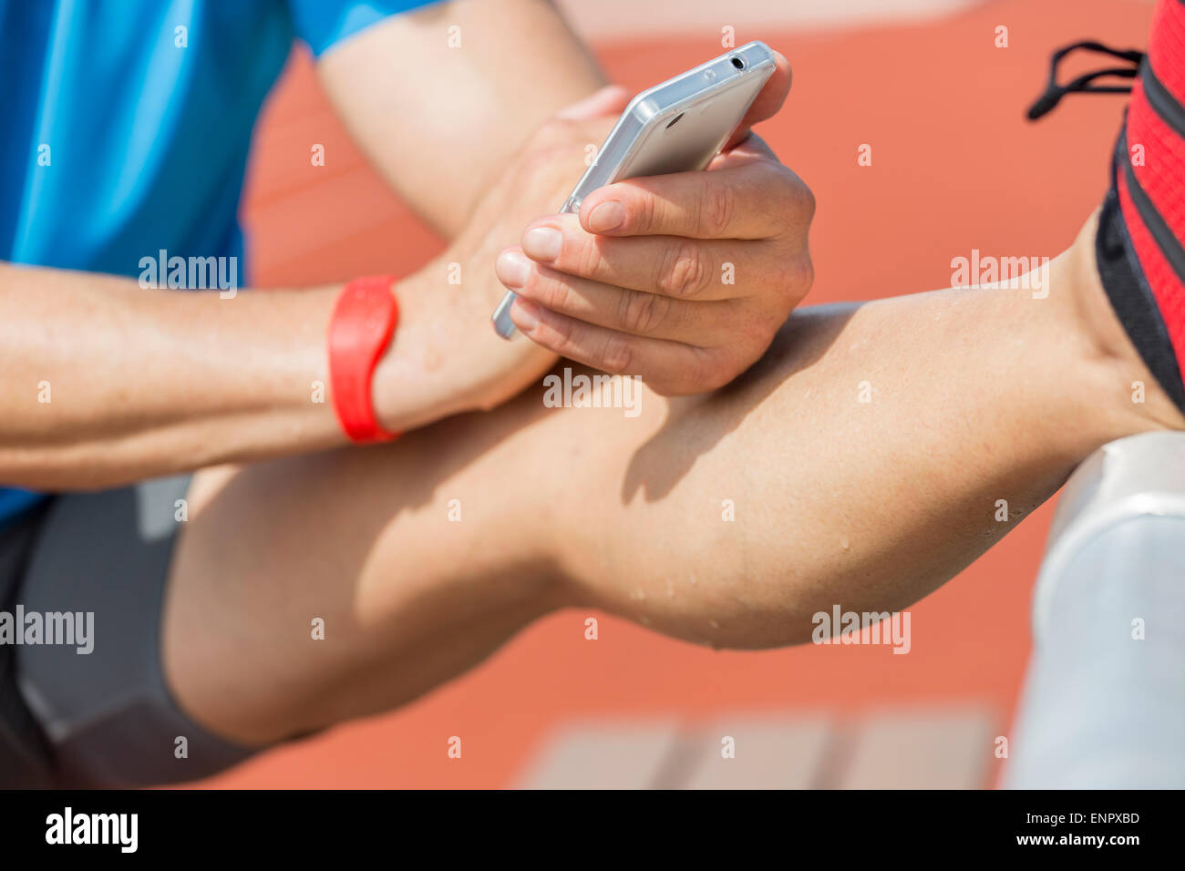 La transpiration est l'athlète qui s'étend après la formation et vérifie son résultats de remise en forme sur son téléphone intelligent. Banque D'Images