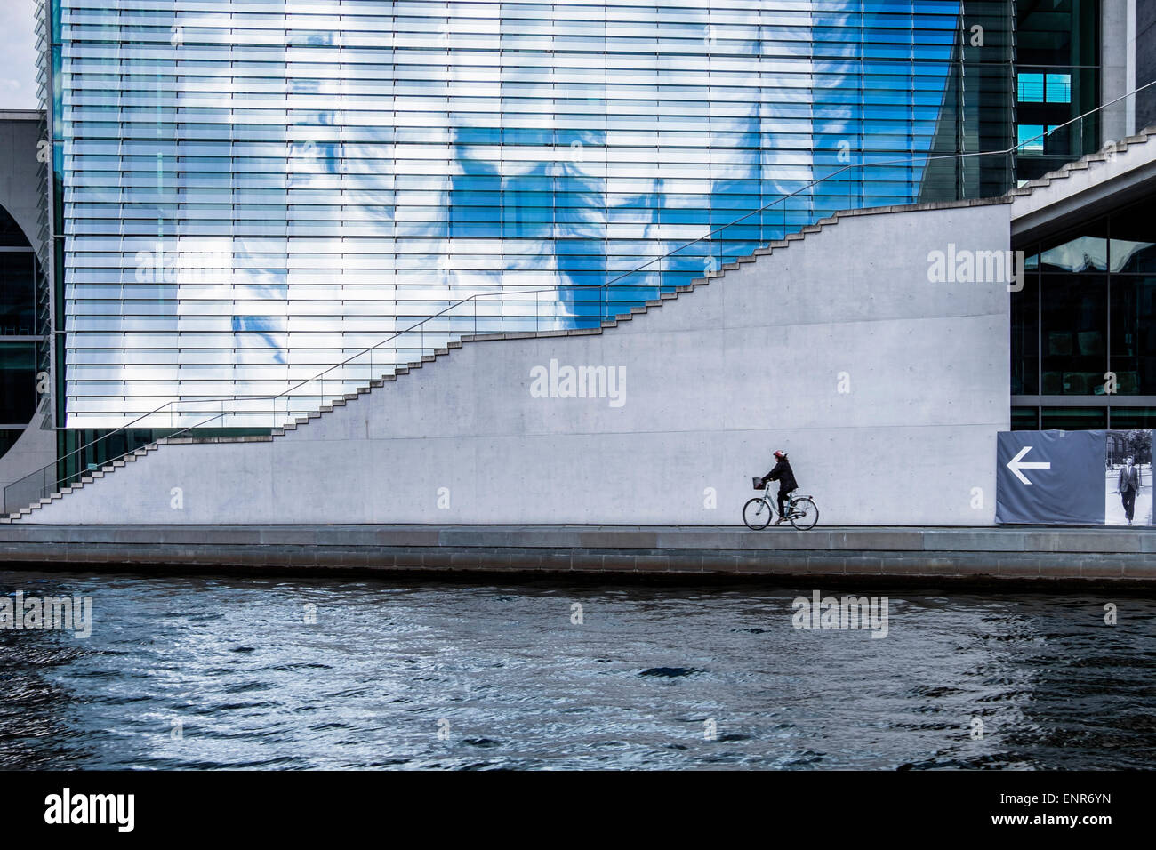Ciel dramatique au reflet dans la vitre de l'Lueders-Haus-Marie-Elisabeth moderne et lone woman cyclist, Spree, Berlin Banque D'Images