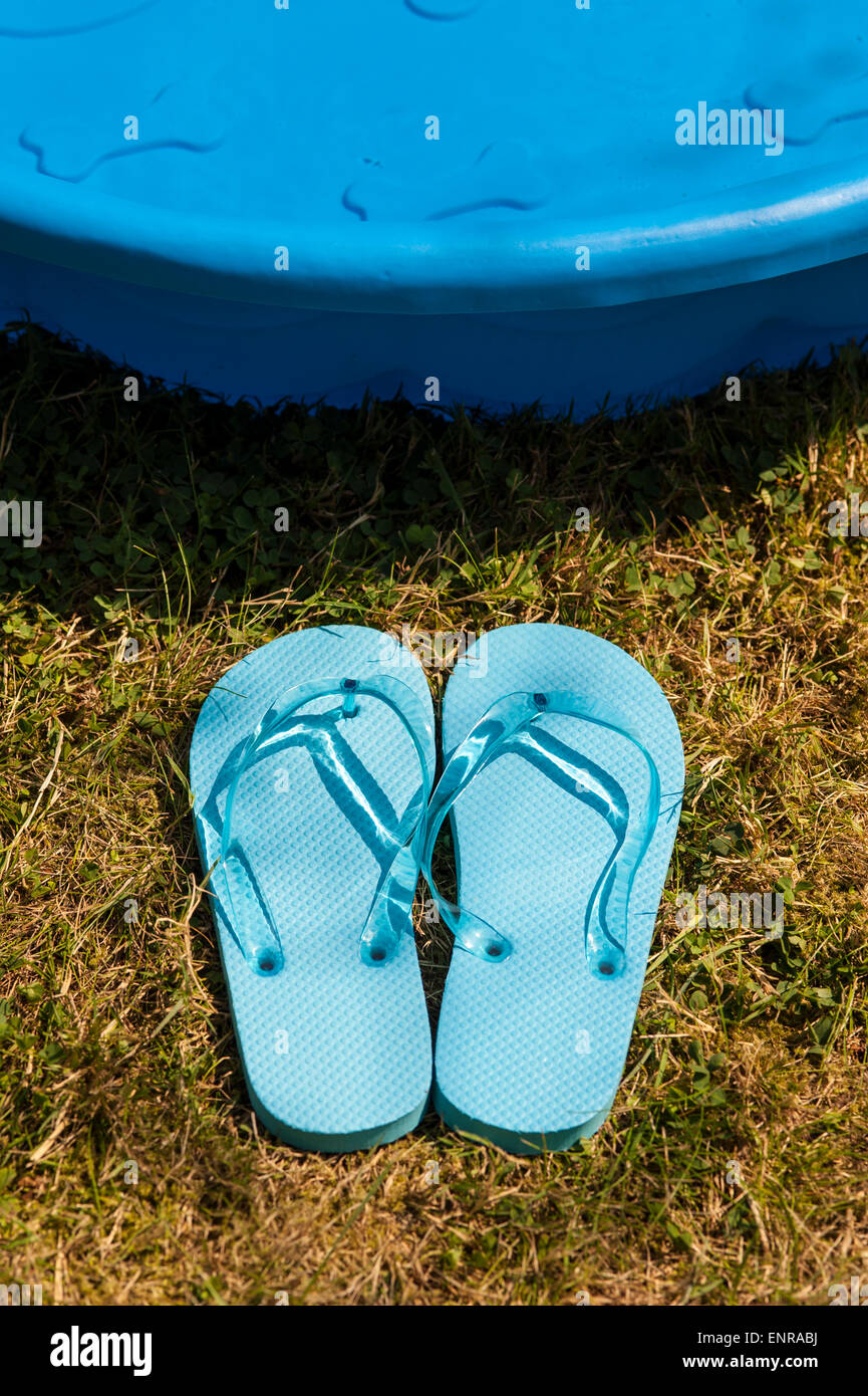 Tongs bleu le long du côté de la piscine Banque D'Images