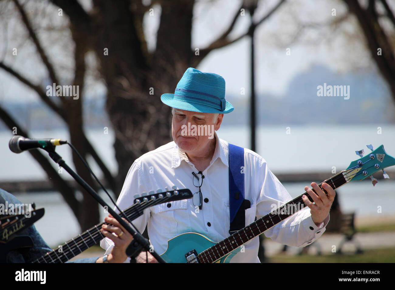 Un homme âgé portant un musicien light blue hat jouant de la guitare sur un trottoir. Banque D'Images