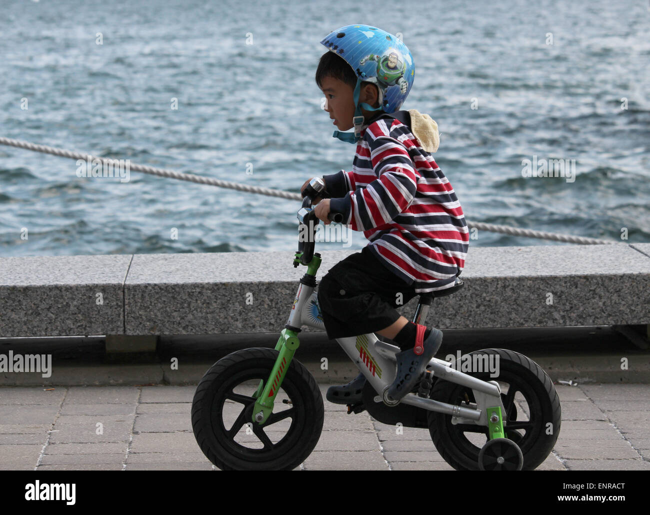 Un jeune garçon en train de rouler à vélo sur la promenade à Harbourfront à Toronto. Banque D'Images