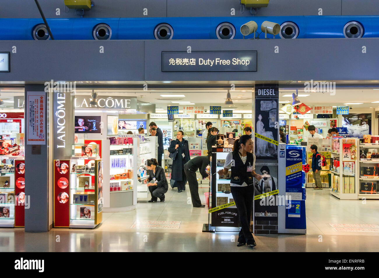 Aéroport de Kansai, KIX, entrée de magasin hors taxes à l'intérieur du salon de départ avec femme promo debout à l'extérieur, et panneaux pour Lancome et Diesel. Banque D'Images