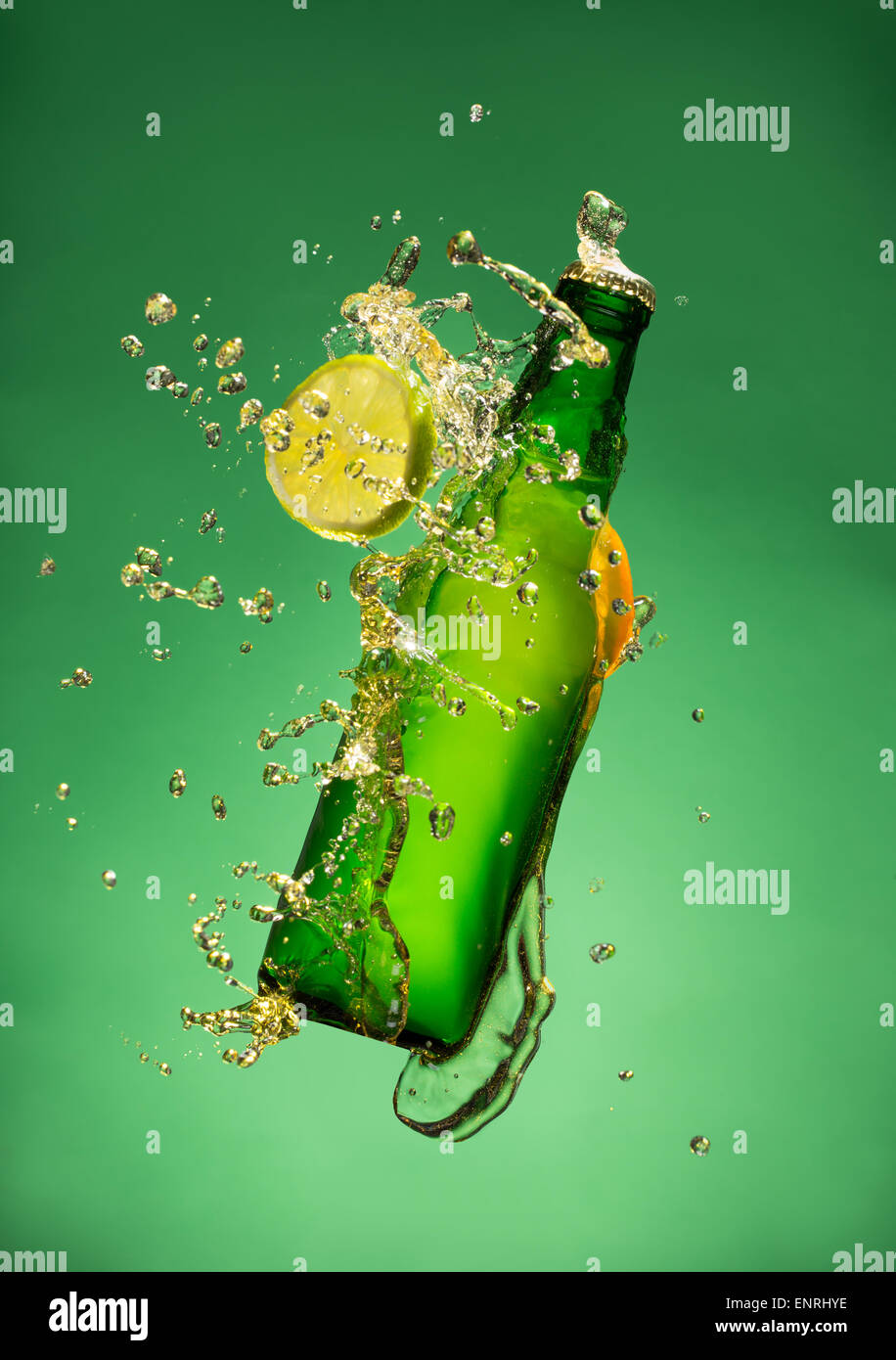 Bouteille de bière de fruits avec splash autour sur fond vert. Banque D'Images