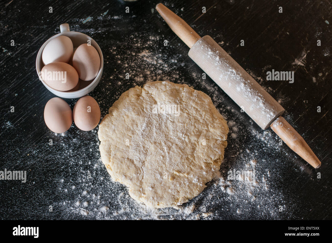 La pâte, oeufs, et d'un rouleau à pâtisserie sur une surface en bois recouvert de farine Banque D'Images