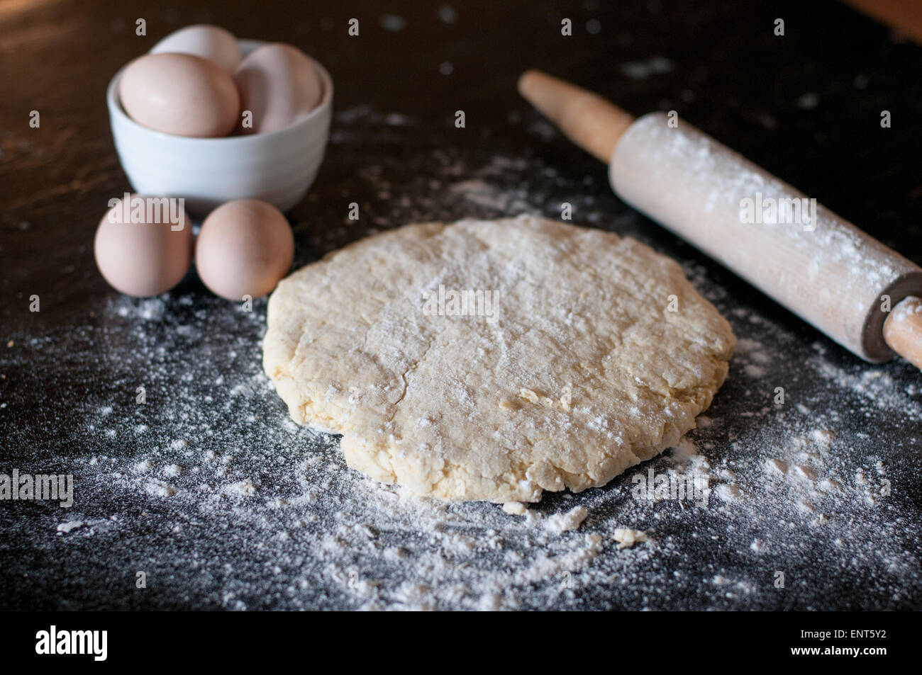 La pâte, oeufs, et d'un rouleau à pâtisserie sur une surface en bois recouvert de farine Banque D'Images