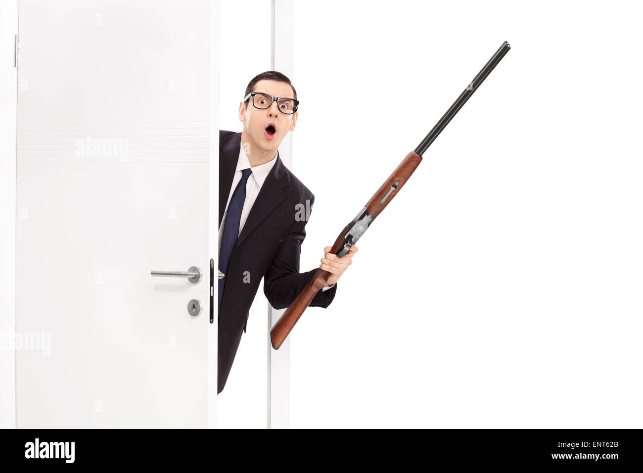 Homme en colère dans un costume noir tenant un fusil carabine et entrer dans une pièce isolé sur fond blanc Banque D'Images