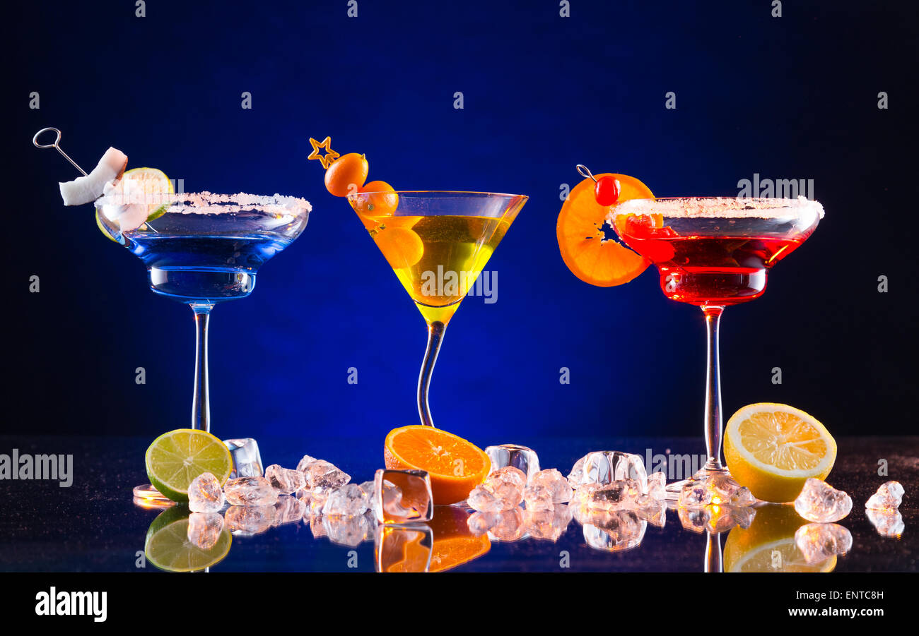 Martini de boissons servis sur une table en verre avec différentes couleurs de fond sombre Banque D'Images