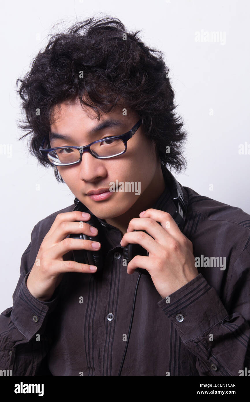 Asian young man wearing head phones looking at camera Banque D'Images