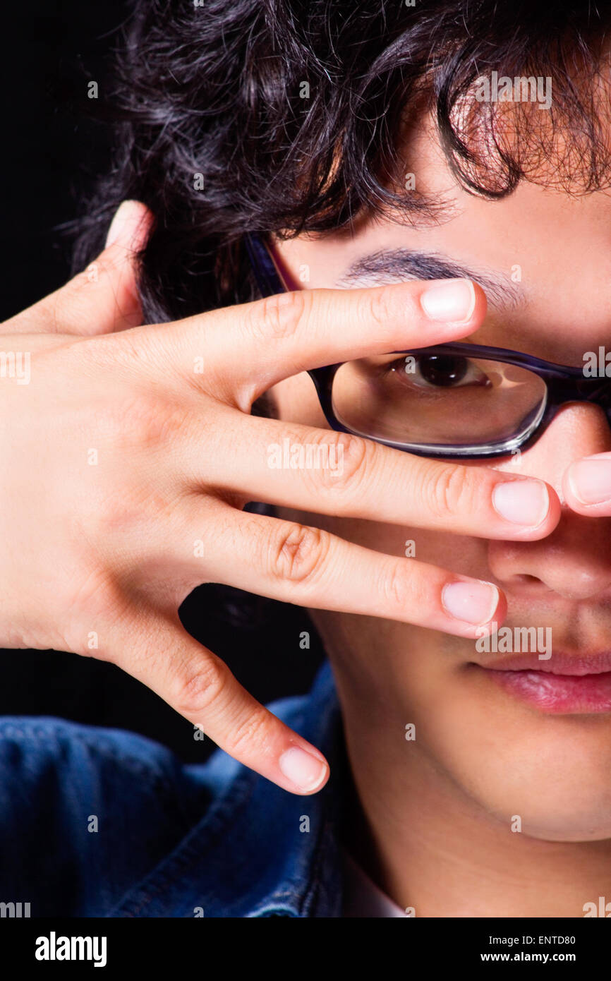 Asian young man looking through mains porter des lunettes Banque D'Images