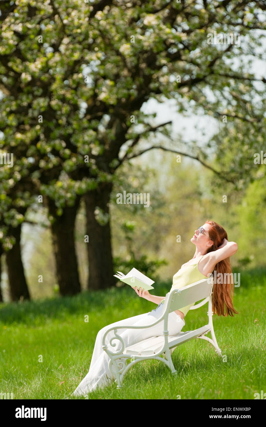 Jeune femme à vous détendre sous les arbres en fleurs au printemps Banque D'Images