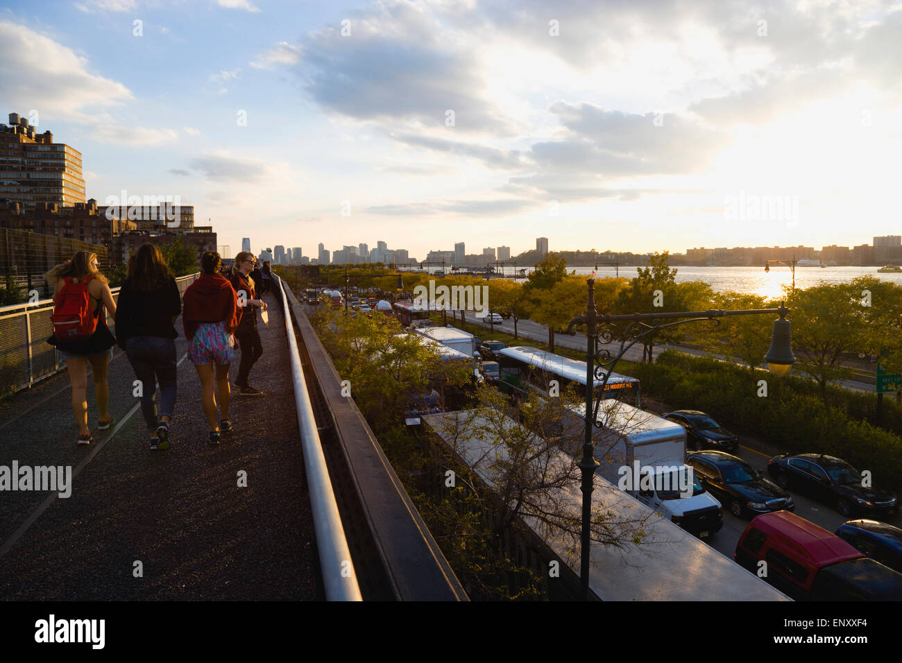 USA, l'État de New York, New York City, New York, Manhattan, côté ouest, les gens marcher sur l'extrémité nord de la ligne haute du parc linéaire élevé à côté 12e Avenue et de la Rivière Hudson au coucher du soleil en automne. Banque D'Images