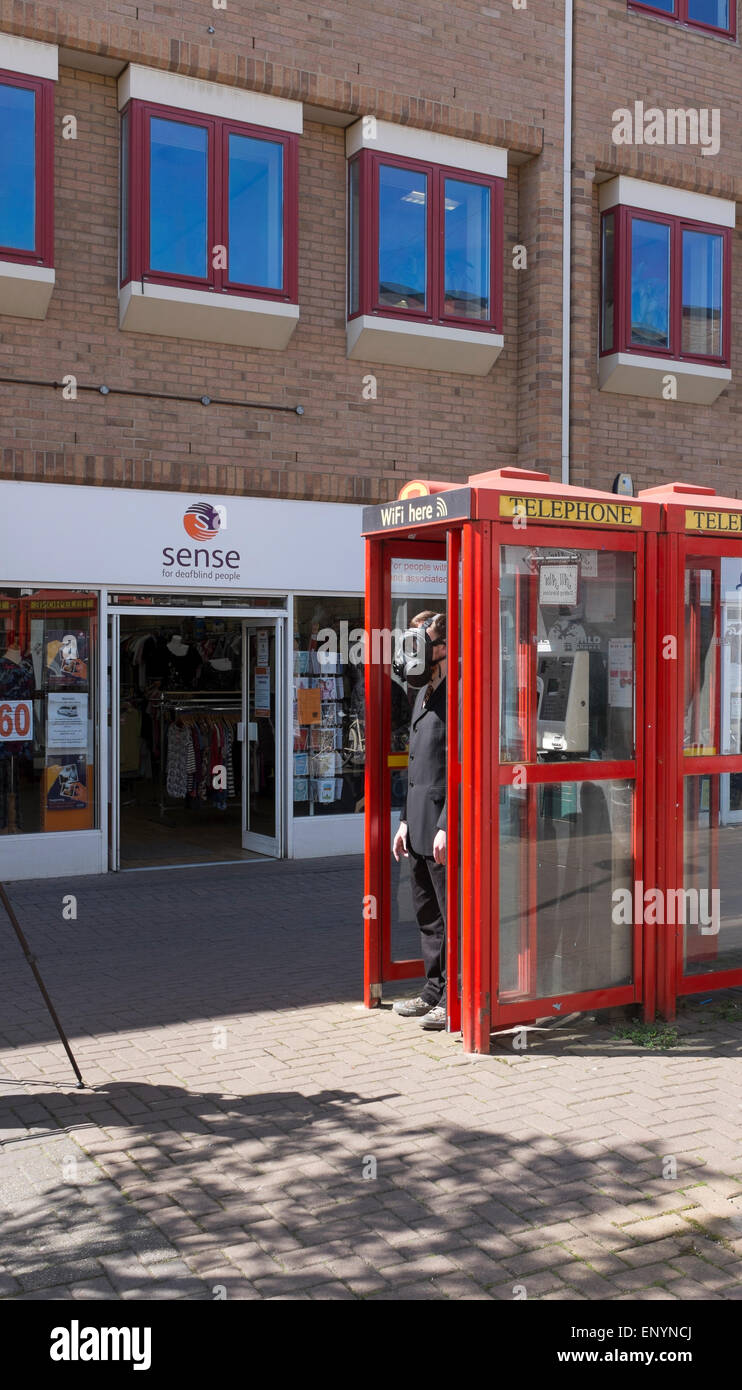 Homme portant un masque à gaz dans la cabine téléphonique qui participent à faire de film vidéo Burleigh Street Cambridge ville Angleterre Banque D'Images