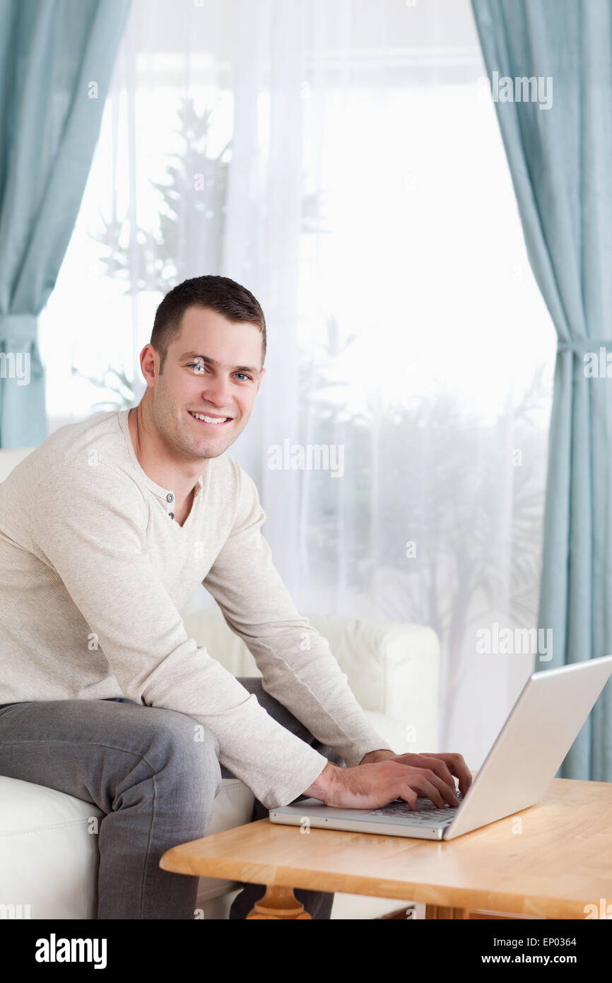 Portrait of a smiling man typing sur son ordinateur portable Banque D'Images