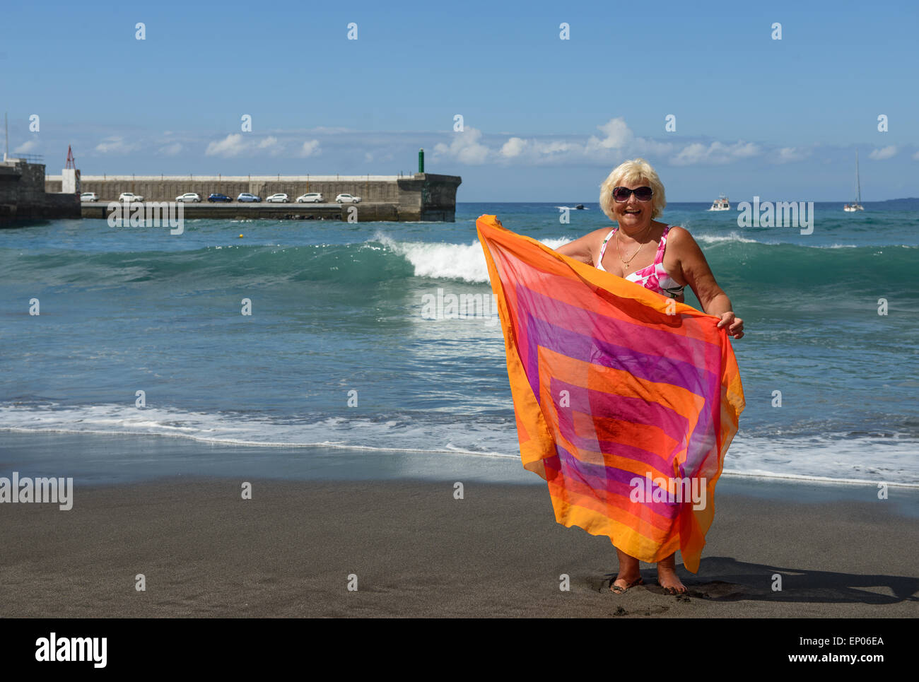 Portrait d'une femme âgée qui est debout sur le sable noir de Guios volcanogène plage avec l'envelopper dans les mains sur sur Banque D'Images