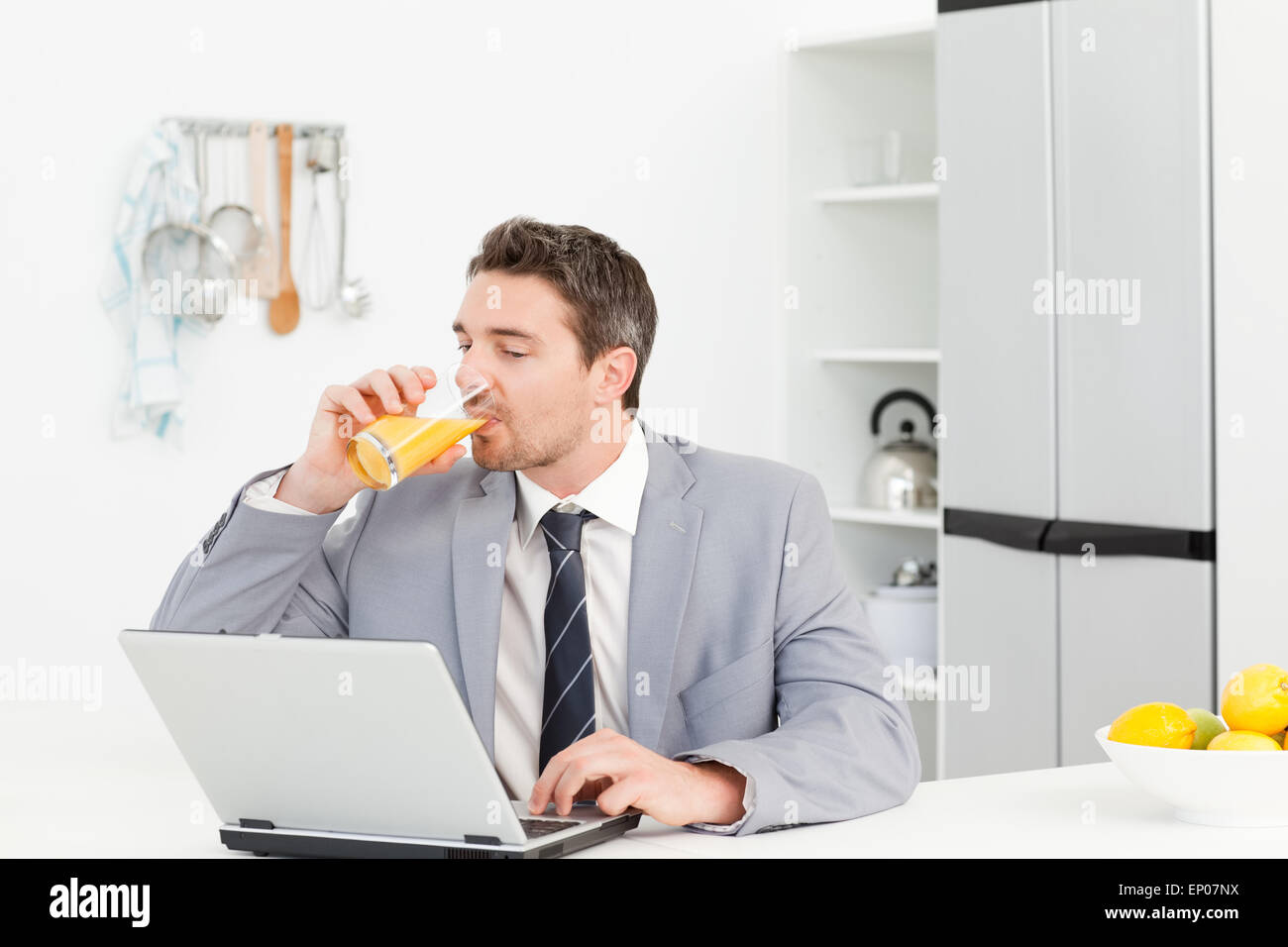 Businessman drinking pendant qu'il est à la recherche à son ordinateur portable Banque D'Images
