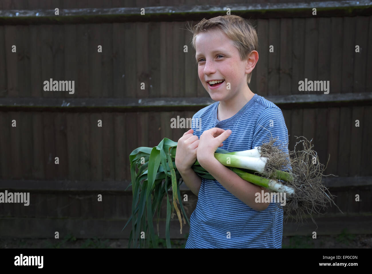 Un garçon heureux avec des poireaux biologiques cultivés cueillis dans le jardin Banque D'Images