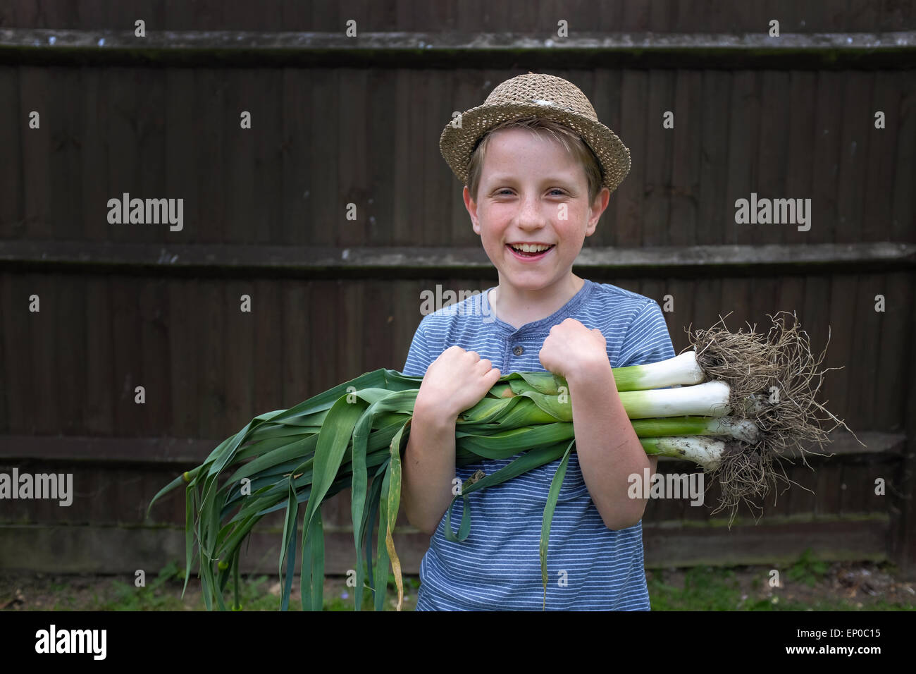 Un garçon heureux avec des poireaux biologiques cultivés cueillis dans le jardin Banque D'Images