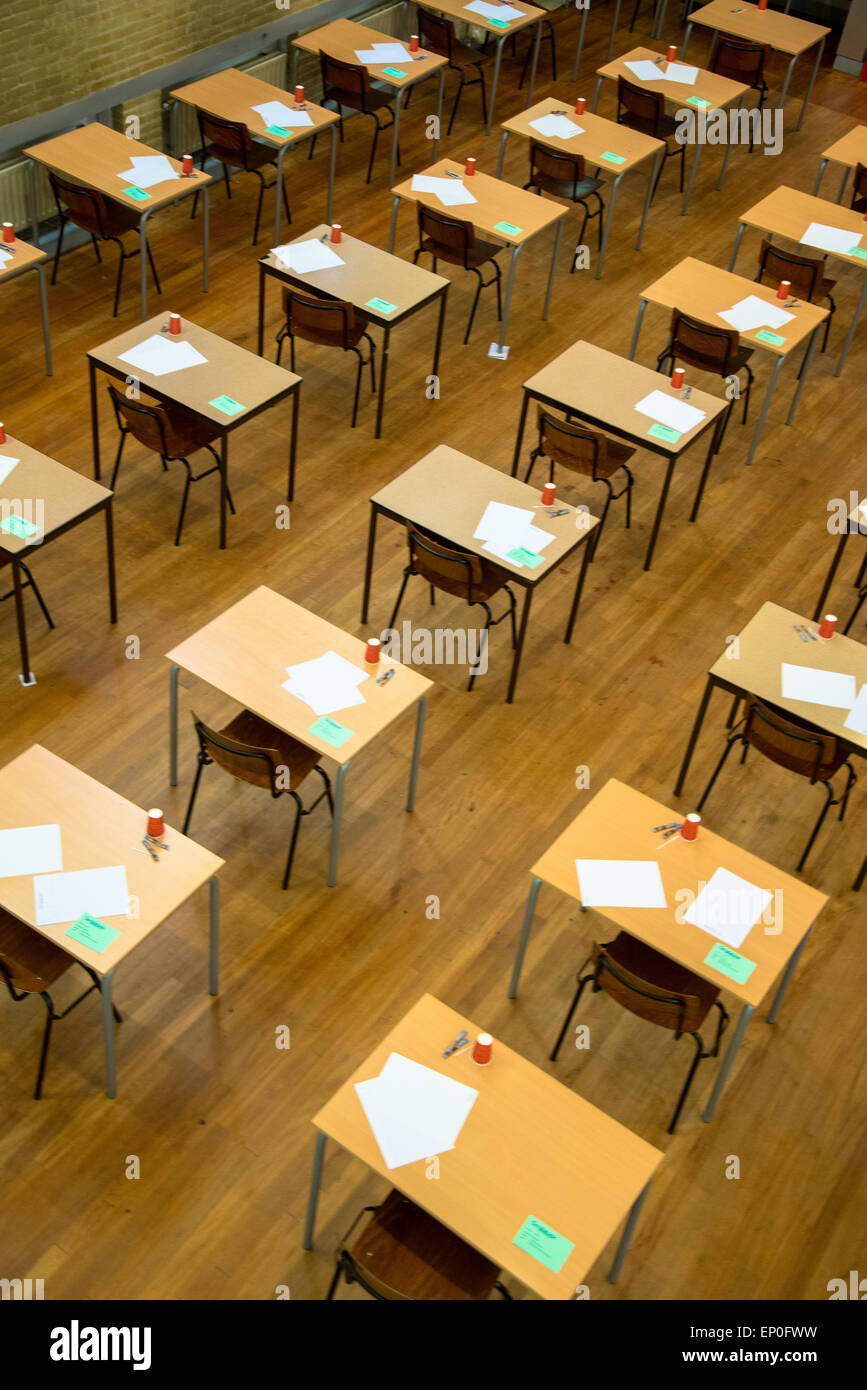 Rangées de tables et chaises avec du papier et des tasses en attente de l'examen à l'école secondaire Banque D'Images