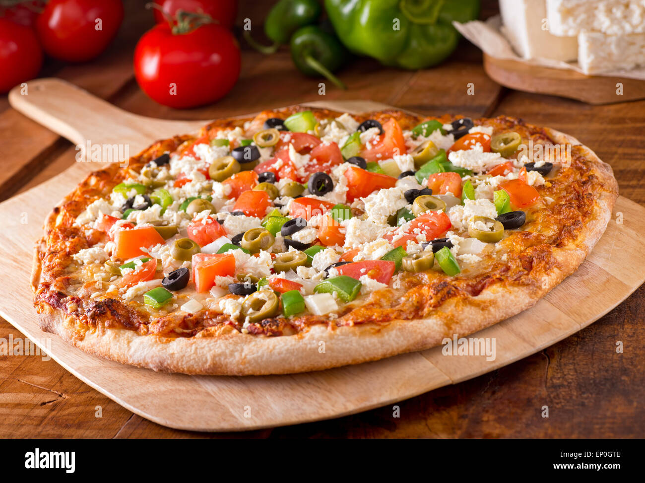 Une délicieuse pizza grecque fraîchement cuits au four avec du fromage feta, olives, tomates et poivron vert. Banque D'Images