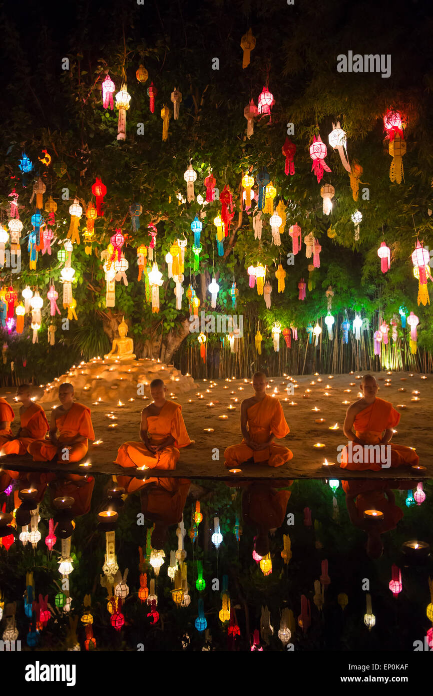 CHIANG MAI, THAÏLANDE - 6 NOVEMBRE 2014 : les jeunes moines bouddhistes méditant assis sous un arbre de bodhi à un festival des lumières. Banque D'Images
