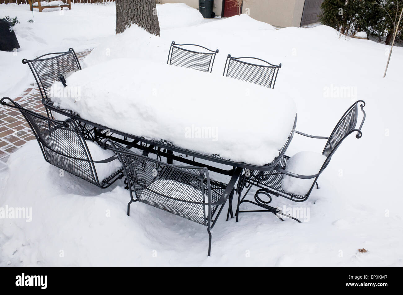 Table et chaises en fer forgé en arrière cour couverte avec de la neige profonde ayant son propre pique-nique d'hiver. St Paul Minnesota MN USA Banque D'Images