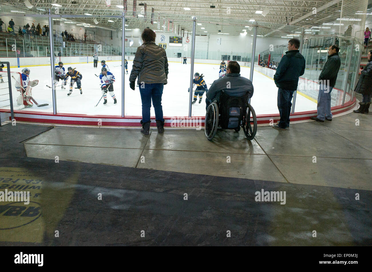 Homme handicapé en fauteuil roulant avec un accès facile à regarder les filles match de hockey. Stillwater Minnesota MN USA Banque D'Images