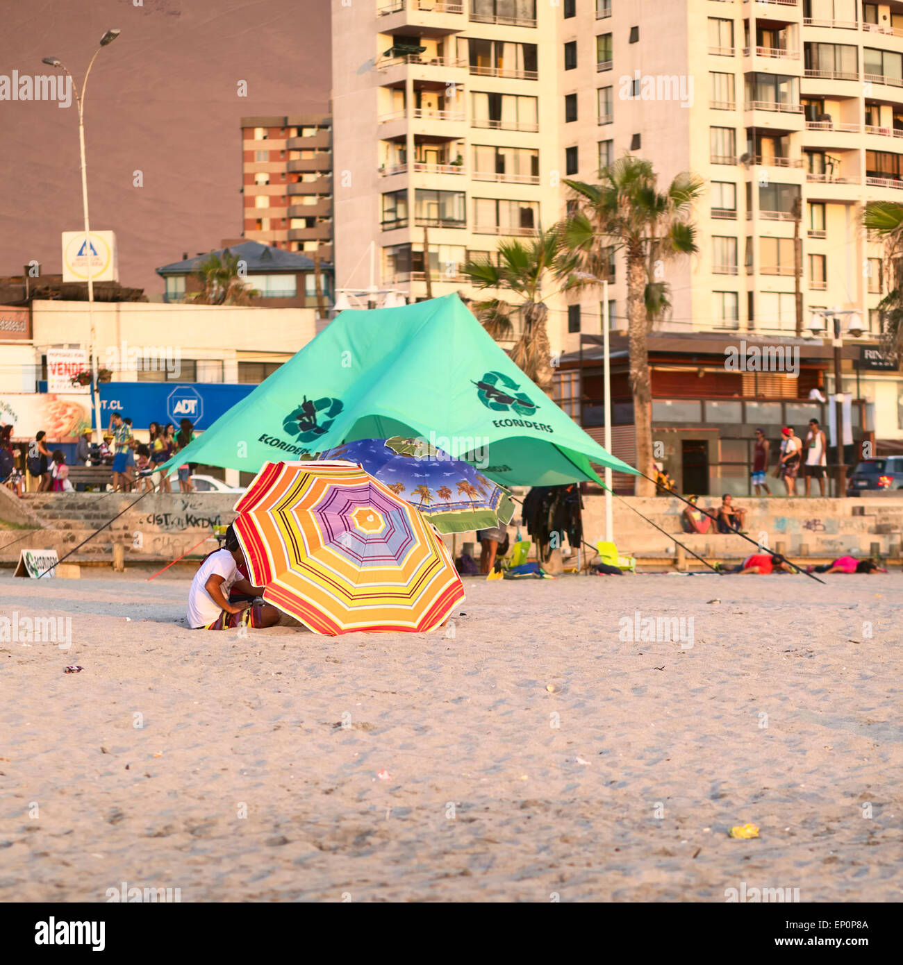 Les jeunes gens assis sous un parasol couché sur le côté sur la plage de Cavancha beach à Iquique, Chili Banque D'Images