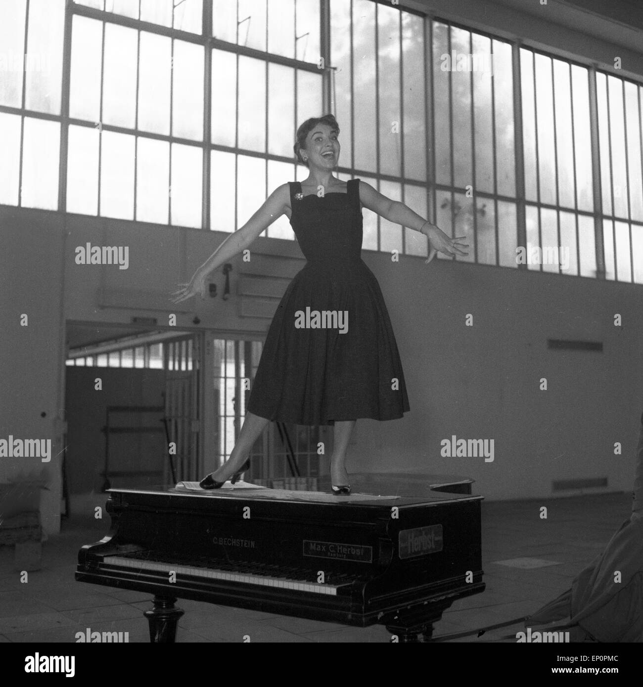 Deutsche Sängerin, Schauspielerin und Kabarettistin Rita Paul tanzt auf einem Flügel, Hambourg 1954. Une chanteuse, actrice allemande Banque D'Images