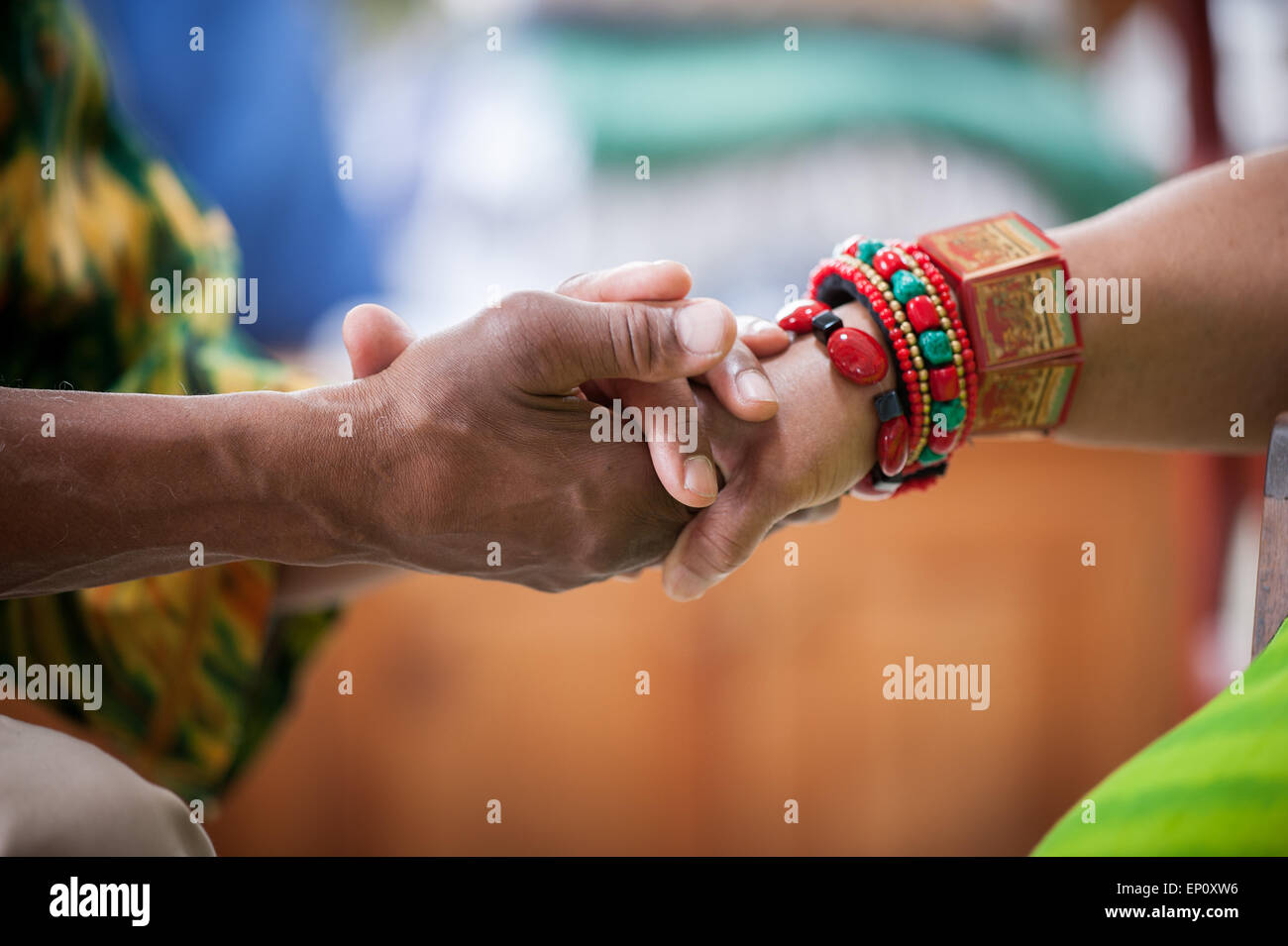 African American man's hands holding sur African American Woman's hand portant des bracelets colorés traditionnels à Baltimore, Ma Banque D'Images