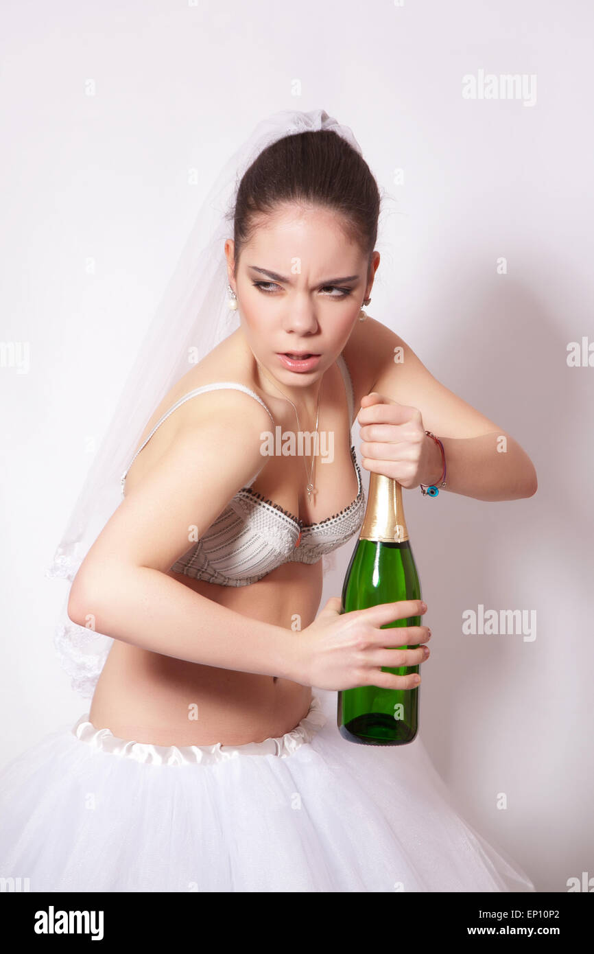 Triste mariée avec une bouteille de champagne à la main, vêtus de sous-vêtements et jupe Banque D'Images