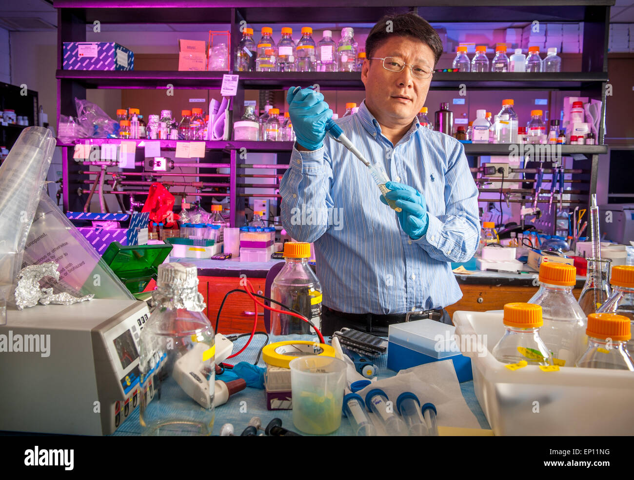 Male scientist in lab à la pipette entourée par l'équipement de laboratoire. Banque D'Images