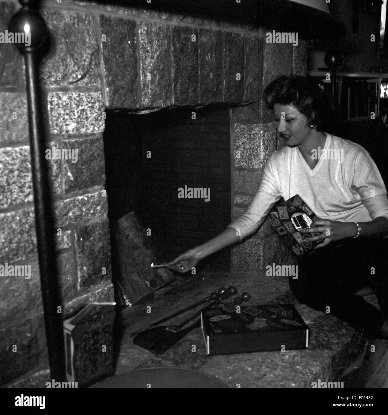 Deutsche Schauspielerin Gisela Lelim Michel zündet den Kamin, un Deutschland 1950 er Jahre. L'actrice allemande2312 éclairage Lelim Michel Banque D'Images