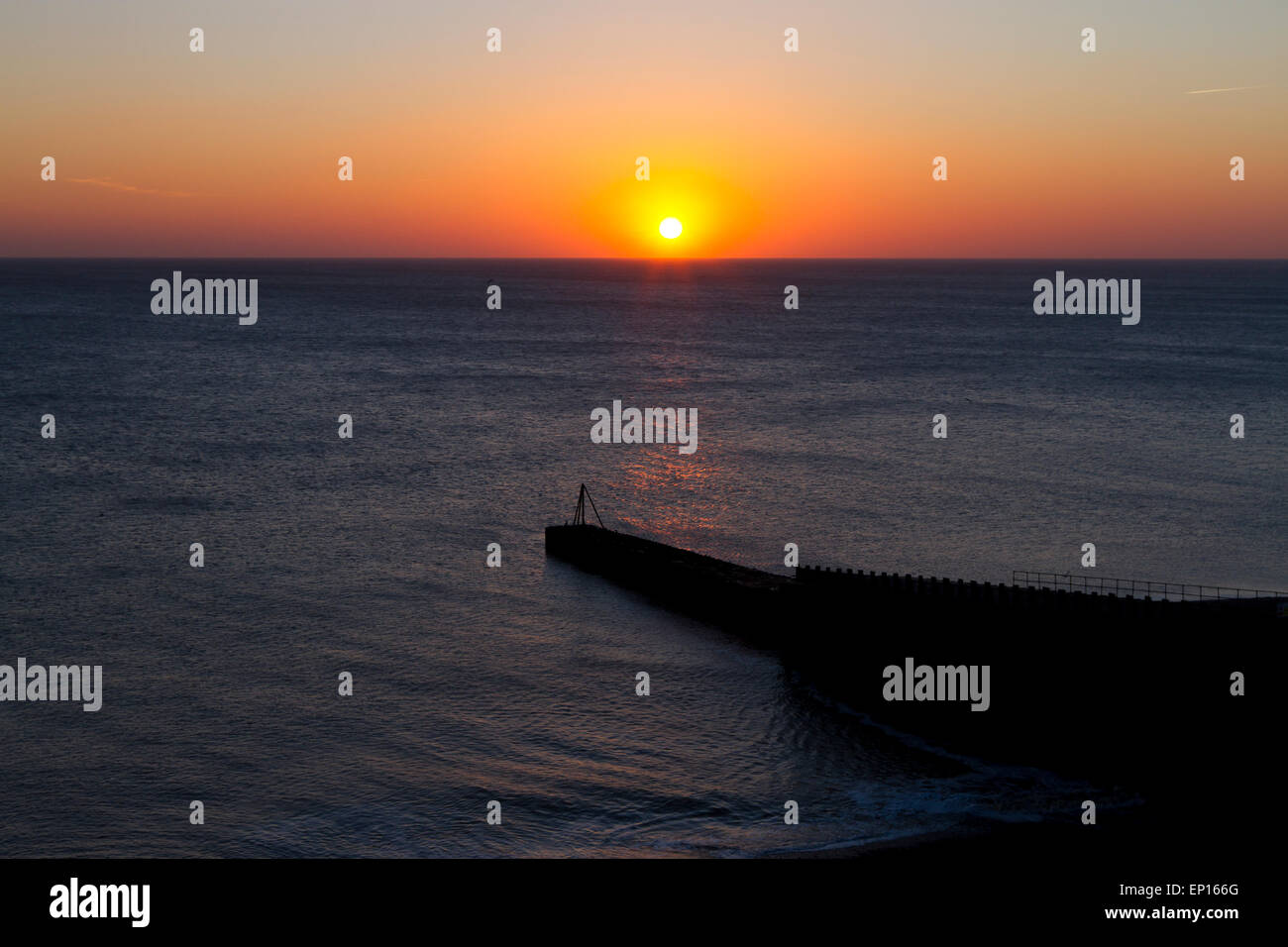 Coucher de soleil sur la mer et d'un brise-lames. Ingelmunster, Sussex, Angleterre. Février. Banque D'Images