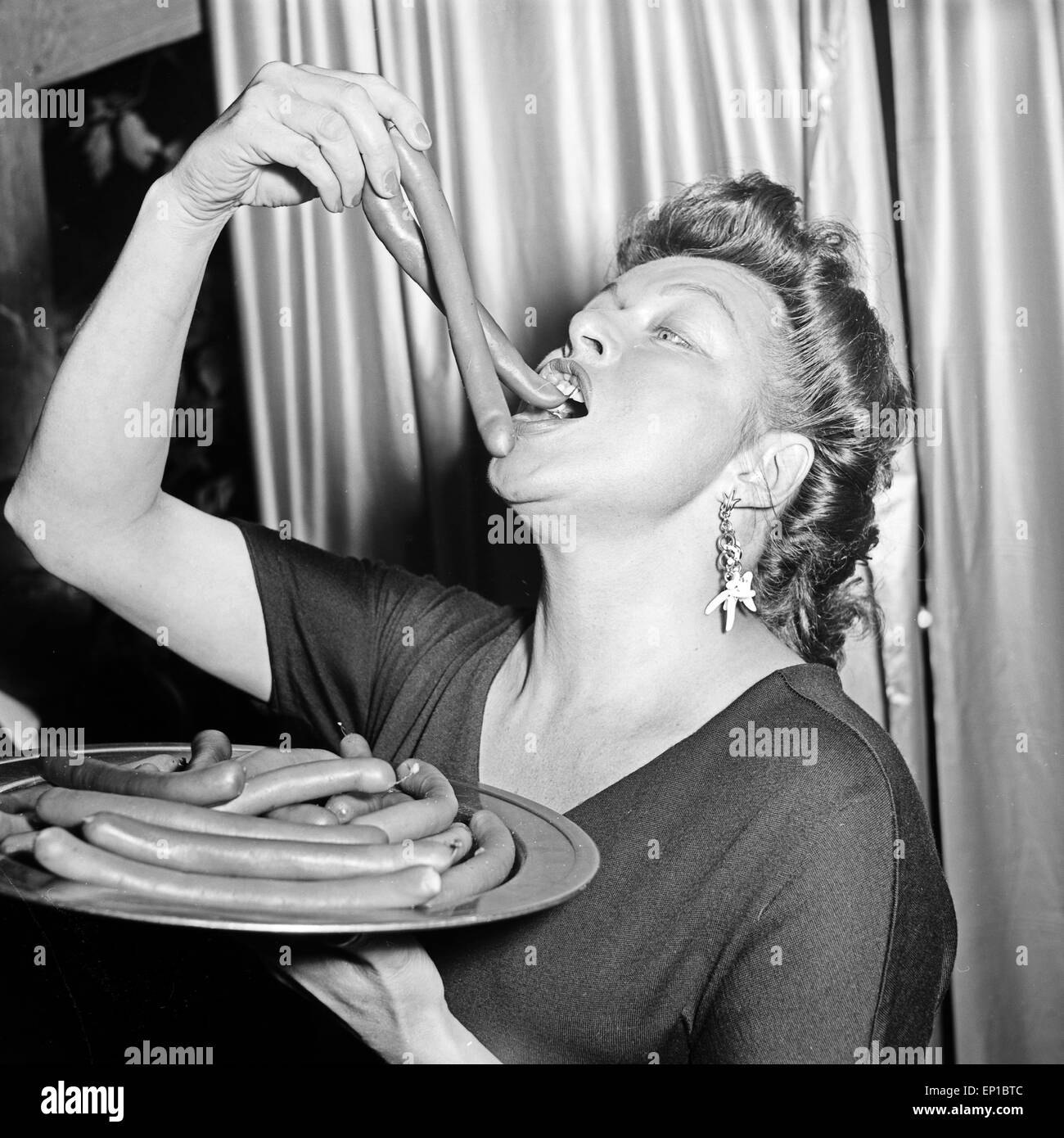 Deutsche Schauspielerin Lotte Rausch ißt ein paar Würstchen, Deutschland 1950er Jahre. L'actrice allemande Lotte Rausch pour manger Banque D'Images