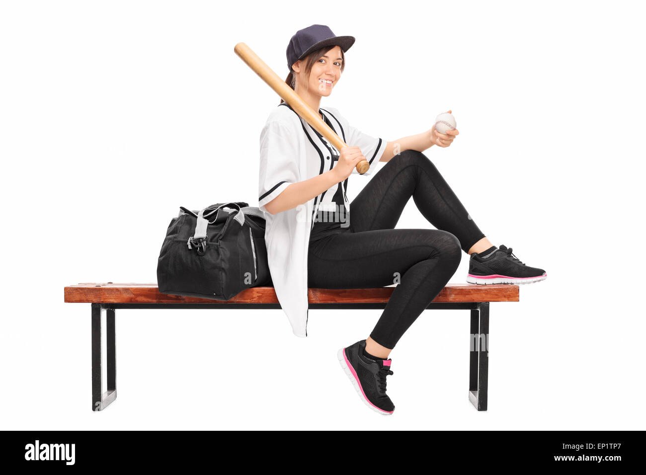 Professionnel de baseball féminin tenant un bâton de base-ball assis sur un banc avec un sac de sport noir à côté d'elle Banque D'Images