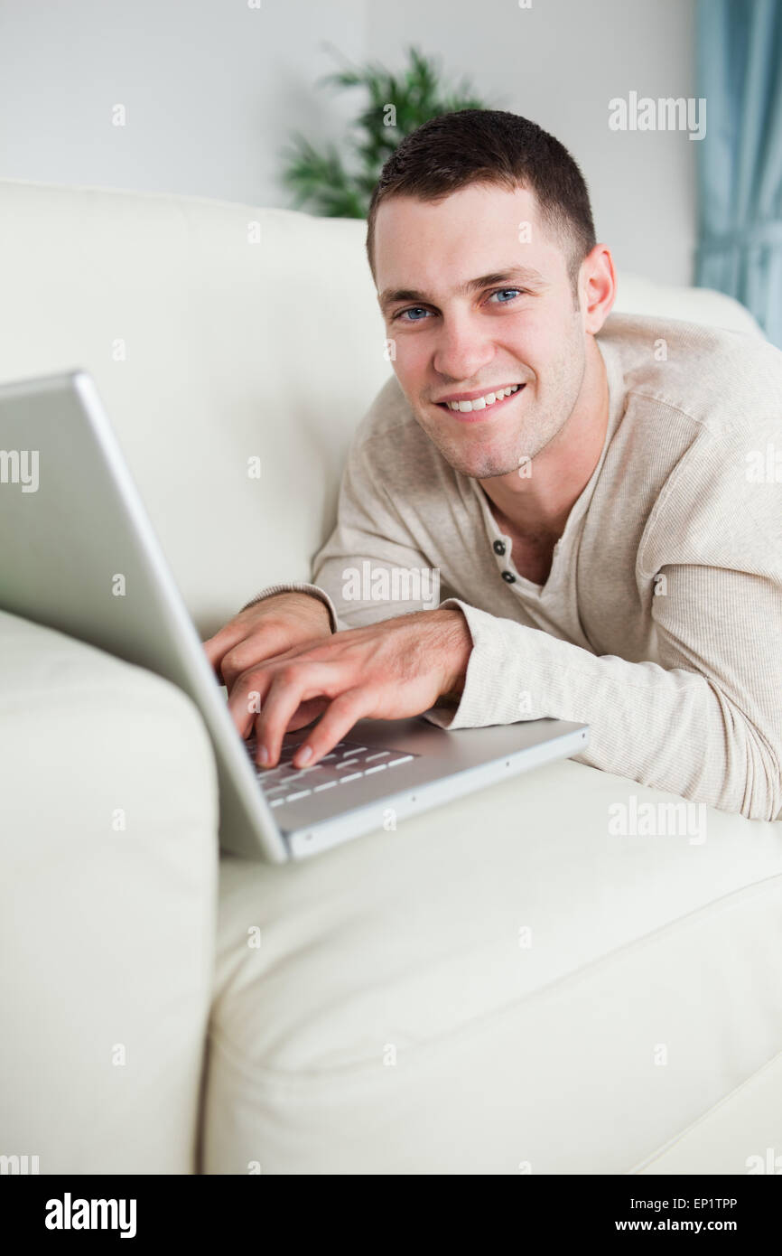 Portrait of a smiling man sitting on a couch with a laptop Banque D'Images