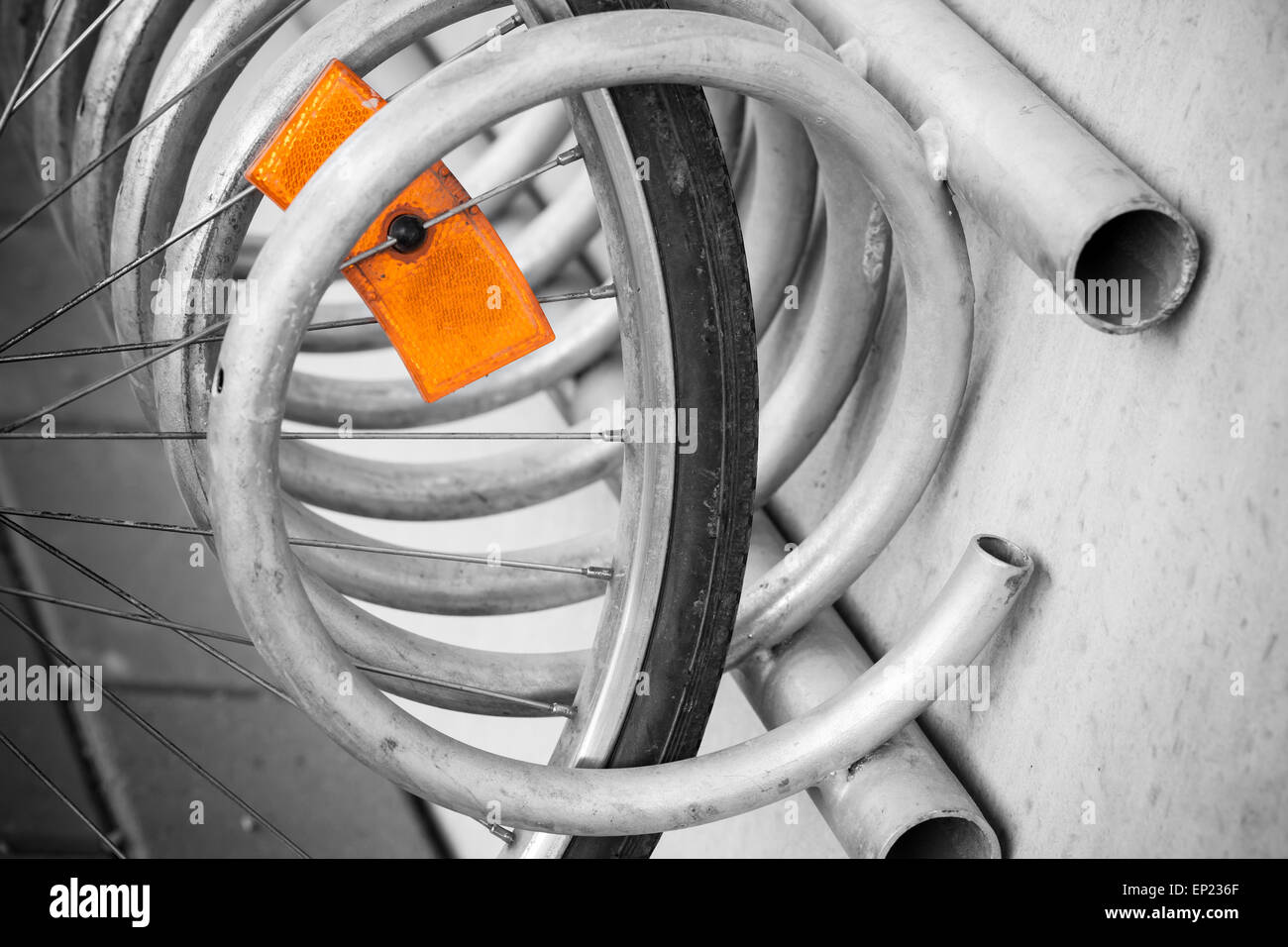 Fragment d'une roue de vélo en stationnement avec réflecteur orange vif, selective focus avec DOF peu profondes Banque D'Images