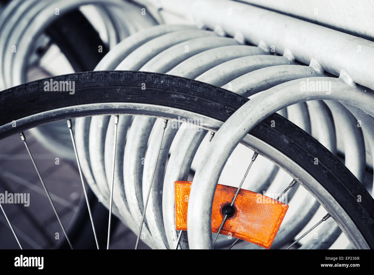 Fragment d'une roue de vélo en stationnement avec réflecteur orange vif, photo aux tons vintage Banque D'Images