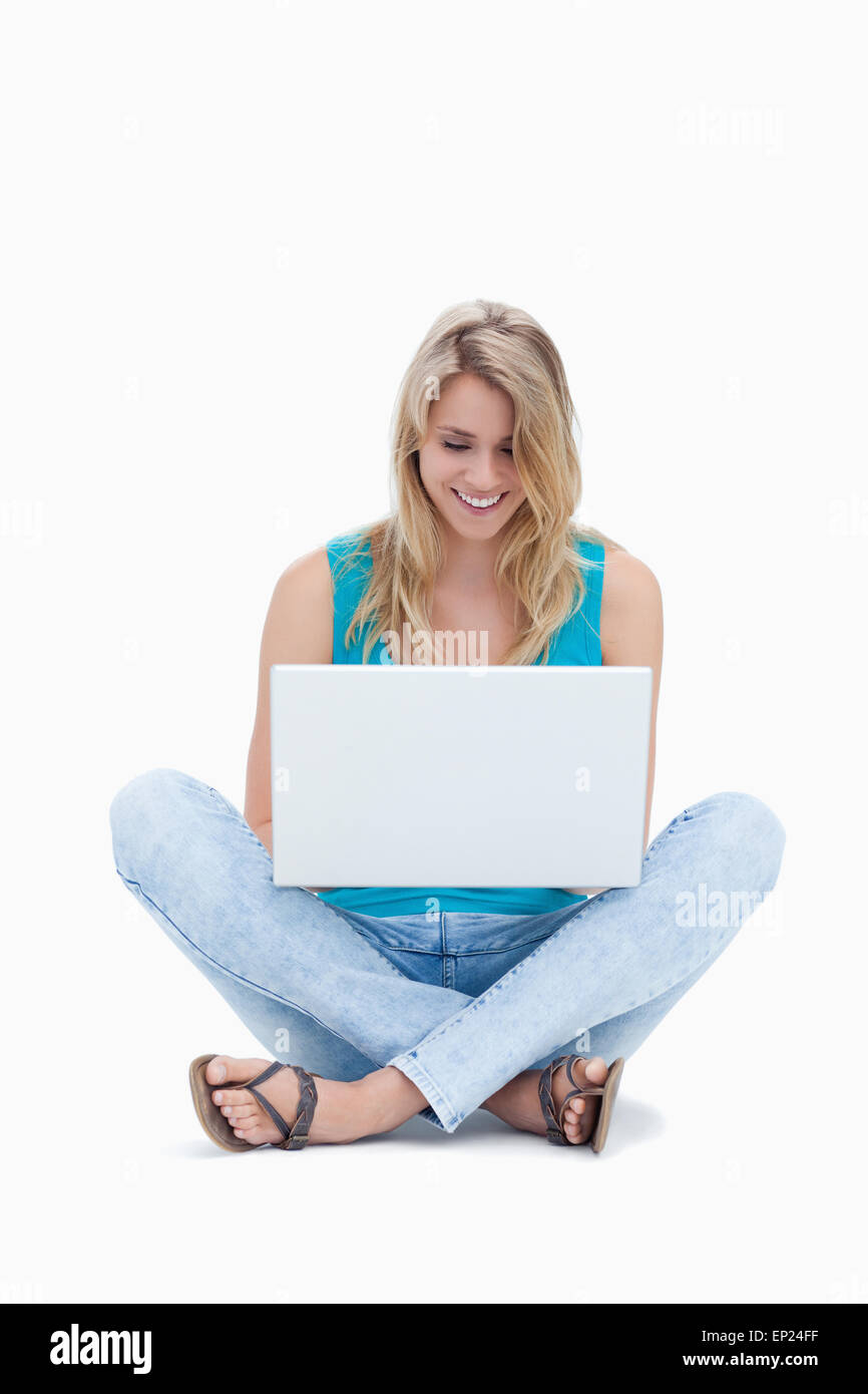 Une femme est assise sur le sol à la recherche de son portable Banque D'Images Une femme est assise sur le sol à la recherche de son portable Banque D'Images