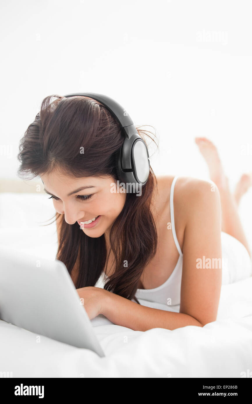 Close up, femme sur le lit à l'aide d'une tablette et d'écouteurs avec les jambes croisées Banque D'Images Close up, femme sur le lit à l'aide d'une tablette et d'écouteurs avec les jambes croisées Banque D'Images